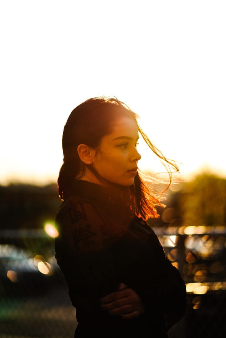 Femme brune les cheveux au vent qui regarde vers l'horizon, de profil vers la droite.