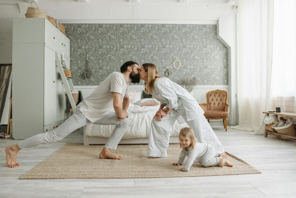 a couple kissing near their daughter crawling on the floor