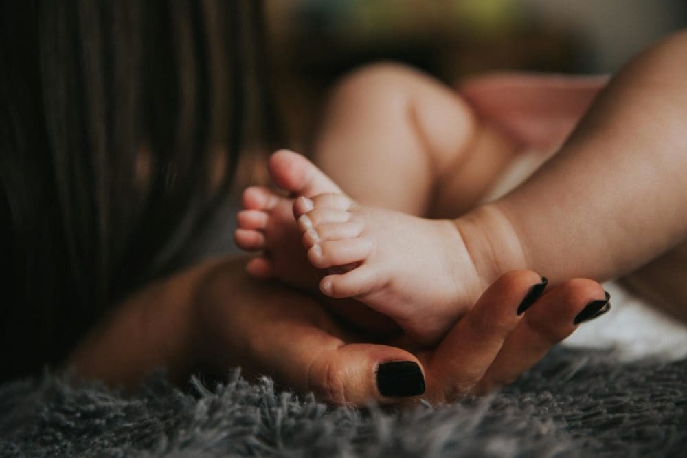 Zoom sour la main d'une femme tenant des pieds de nourrisson