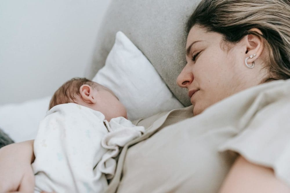mother with baby sleeping on bed